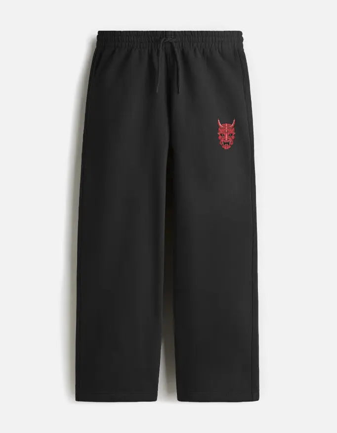 Black sweatpants with elastic waistband and red demon face embroidery on left pocket