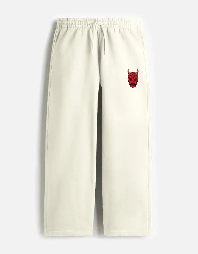 Cream-colored sweatpants with elastic waistband and red devil face embroidery on left pocket