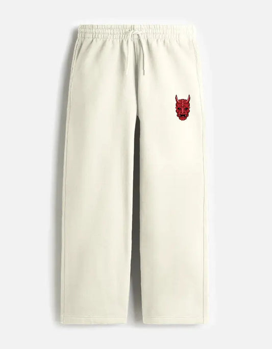Cream-colored sweatpants with elastic waistband and red devil face embroidery on left pocket