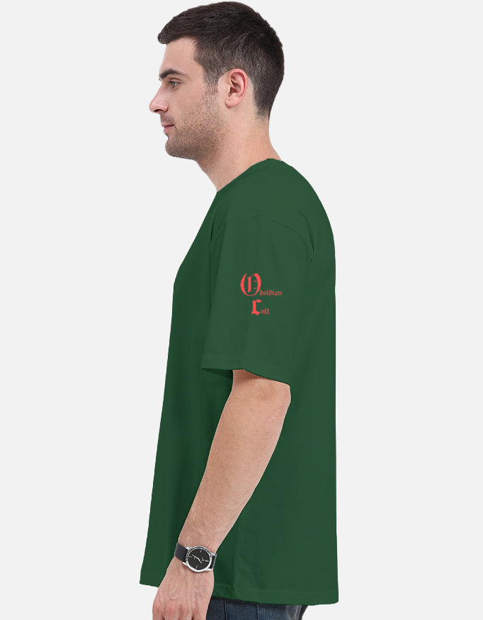 Man wearing forest green short sleeve t-shirt with small red graphic on left shoulder, side profile